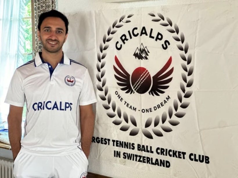 A Cricalps player in club kit beside the club banner