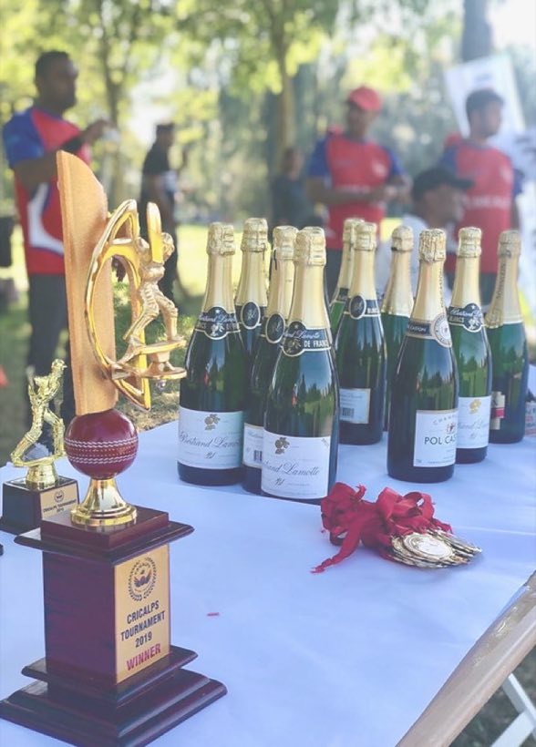 A trophy on a presentation table beside a row of champagne bottles