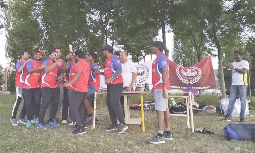 Players in red kit beside the club flag at the presentation table