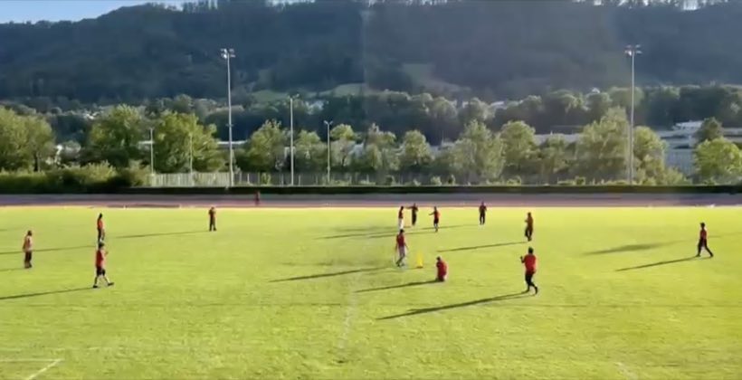 A match seen from a distance across the ground, hills on the horizon