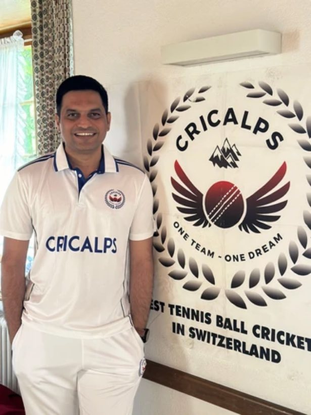 A player in the white Cricalps shirt standing beside the banner indoors