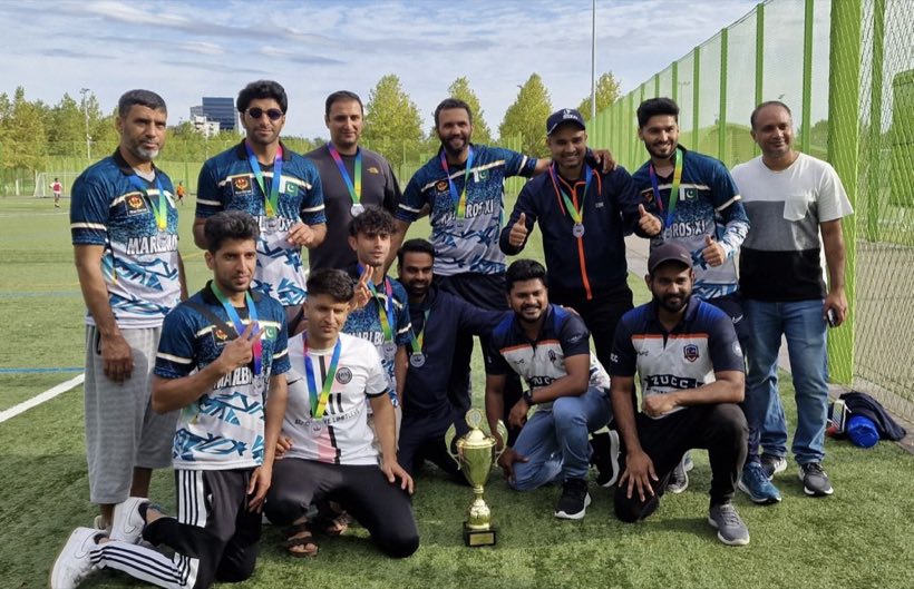 The squad grouped around a trophy on the artificial pitch