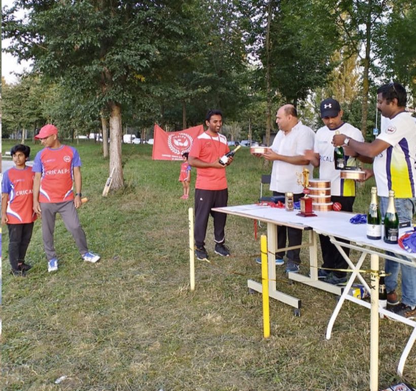 Members around the presentation table outdoors, club flag and trophies set out