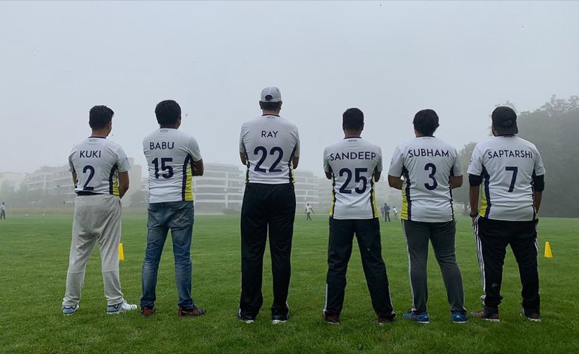 Five players seen from behind in a misty ground, names and squad numbers across their shirts