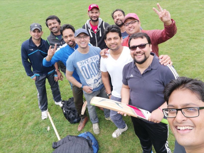 A group selfie on the outfield, one player holding a bat